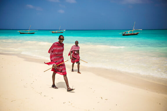 Two Masai walk along a beach in Zanzibar