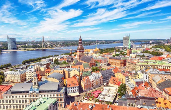 Aerial view of a city with a mix of historic and modern buildings, a river running through it, and a clear sky.