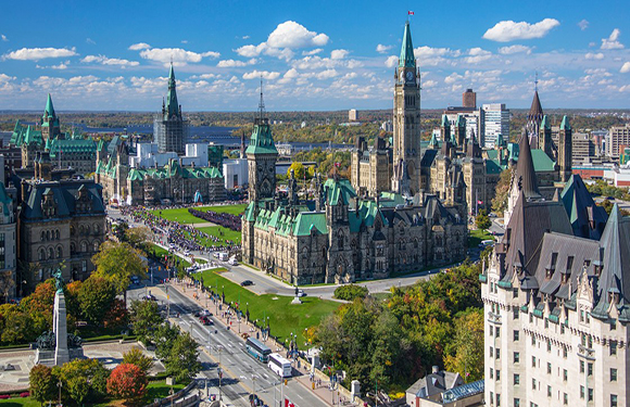 Aerial view of a cityscape with historic buildings, green spaces, and a clear blue sky.