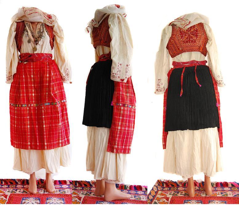 Three mannequins in folk costumes are displayed on a rug, each from a different angle. The outfits are red, white, and black with embroidery.