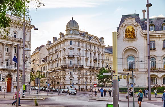 A European city street view featuring classic architecture, pedestrians, and clear skies.