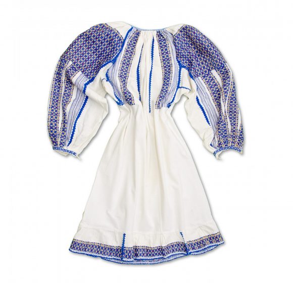 A traditional white dress with blue embroidered patterns and puffy sleeves, displayed against a plain background.