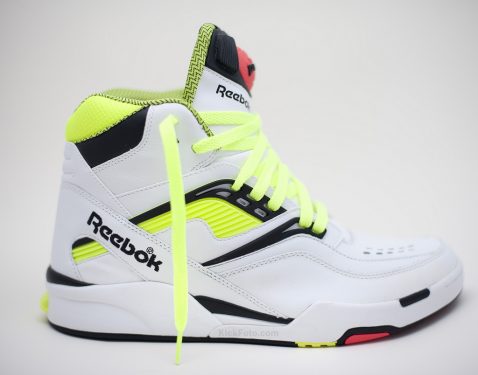 A white high-top Reebok sneaker with neon yellow accents and laces, featuring the Reebok logo on the side.