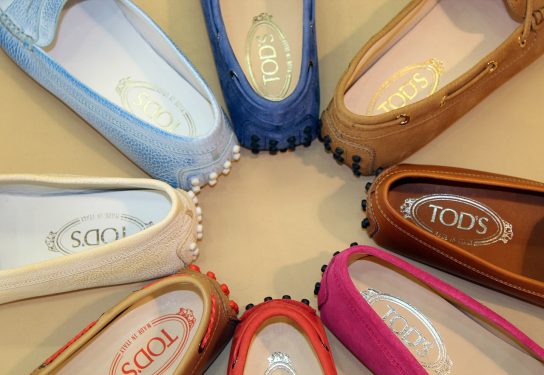 A collection of colorful Tod's brand shoes arranged in a circle on a light background.