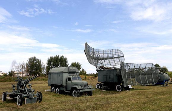 A military radar system with large antenna dishes mounted on trucks in an open field.