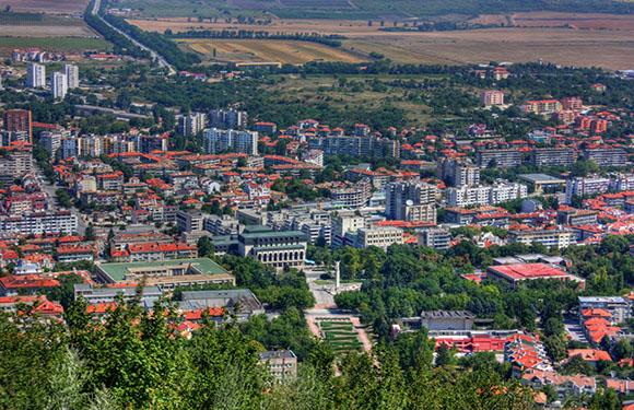 Aerial view shows a densely built city amidst greenery, clearly separating urban development and nature.