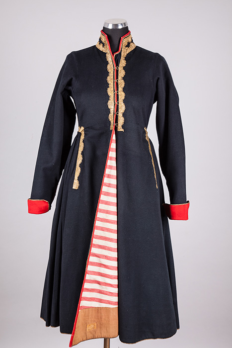 A navy blue coat with red cuffs and gold trim, paired with a red and white striped skirt, is displayed on a mannequin.