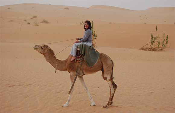 A person riding a camel in a desert setting.