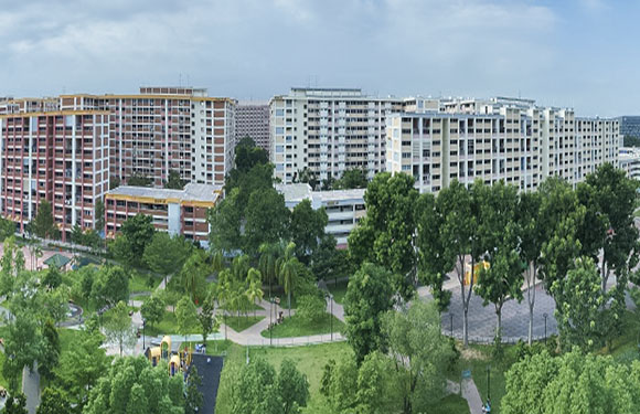 Aerial view of a peaceful suburban residential area with multi-story apartments, greenery, roads and pathways.