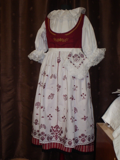 A traditional dress with a white blouse and a patterned skirt on a mannequin.