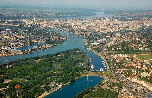 Aerial view of a city with rivers, bridges, buildings, and green areas.