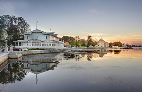 A serene waterfront scene at dusk with a reflection of buildings on the calm water.