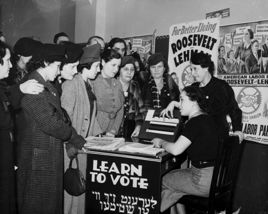 Historical photo shows people learning to vote, with Roosevelt and Lehman campaign posters in the background.