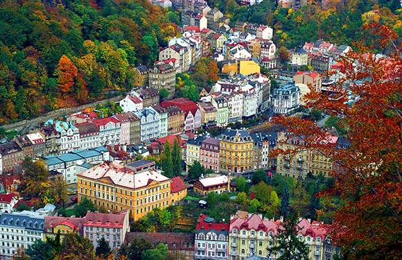 Aerial view of a colorful European town with dense buildings surrounded by autumn trees.