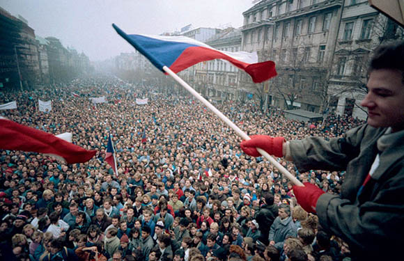 A person holding a flag with a large crowd of people in the background.