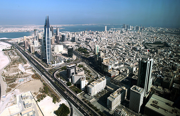 Aerial view of a modern cityscape with dense buildings, prominent skyscrapers, and a clear sky.