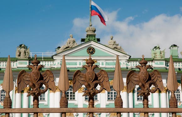 An image of a historic building with a green roof and ornate sculptures on the facade. A flag is flying atop the central part of the building.