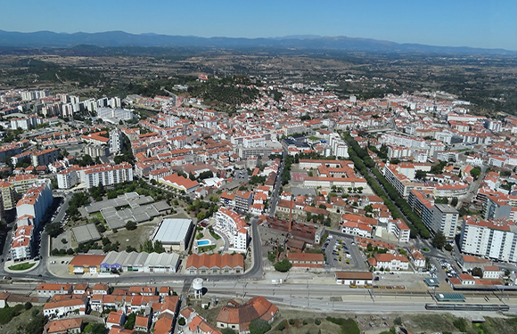 Aerial view of a town with dense building clusters, intersecting streets, and surrounding greenery.