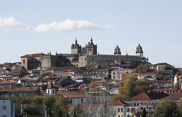 A panoramic view of a historic city with traditional buildings and a prominent cathedral with twin towers on a hilltop.