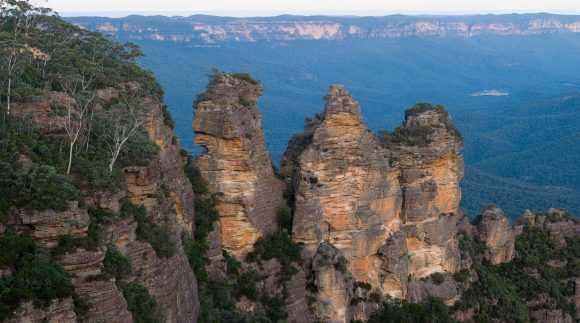 A scenic view of the Three Sisters rock formation at the Blue Mountains in Australia during daylight.