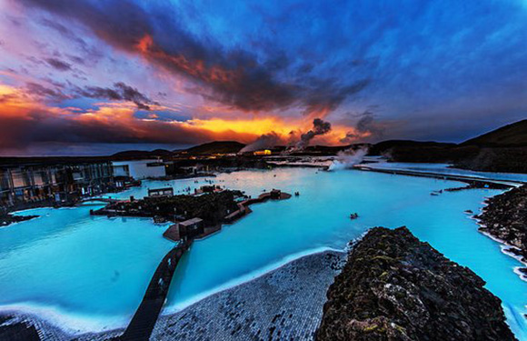 A sunset image of Iceland's Blue Lagoon spa, with steamy waters, colorful skies, and spa facilities.