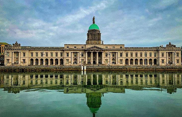 A neoclassical building with a large dome and a reflection on the water in front of it.