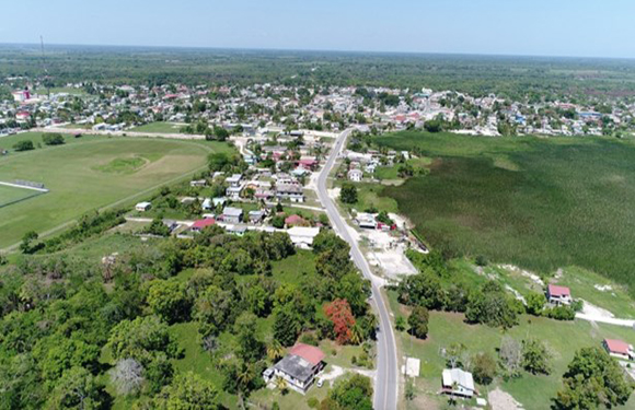 Aerial view of a small town with scattered buildings, roads, and green areas.