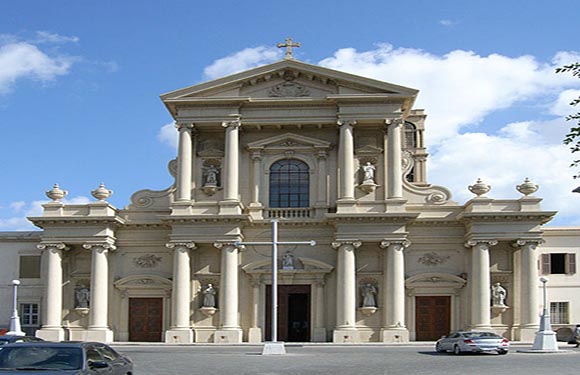 A classical style building with a grand facade featuring columns, statues, and a triangular pediment, under a clear sky.