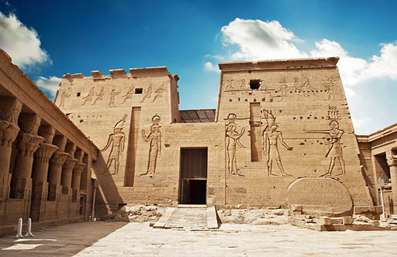 An image of an ancient Egyptian temple with hieroglyphs and carvings on the walls under a clear blue sky.