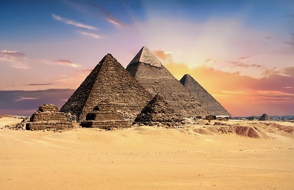 A photo of the Great Pyramids of Giza with a colorful sunset in the background.