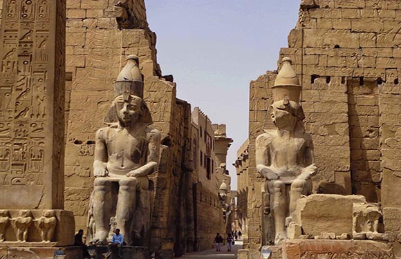 A photo shows two large Egyptian statues with pharaonic headdresses, flanking a hieroglyph-covered walkway.