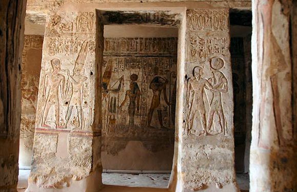 An image of an ancient Egyptian tomb interior with hieroglyphics and wall carvings depicting human figures.