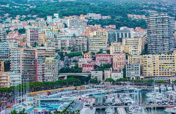 Aerial view of a densely populated city with multistory buildings and a marina filled with boats.