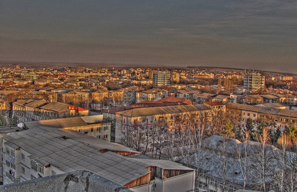 Aerial dusk view of a city, with sunlit buildings and a warm, orange sky.