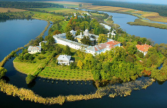 Aerial view of a historic fortress surrounded by a water body with greenery and trees on a sunny day.