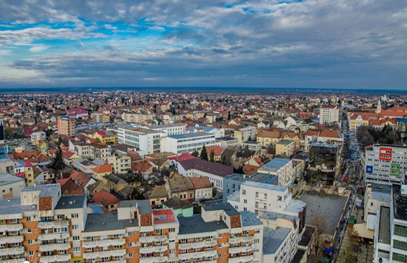 Aerial view of a cityscape with buildings of various heights under a cloudy sky.