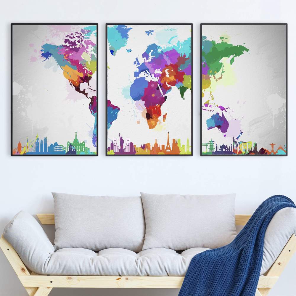 Three-panel canvas art of a colorful world map above a white sofa with a gray cushion and a blue throw blanket.