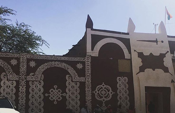 An image of a traditional building with ornate wall designs and a flag on top, under a clear sky.