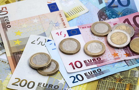 A variety of euro banknotes and coins spread out on a surface.