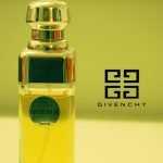 A bottle of Givenchy perfume against a greenish-yellow background.