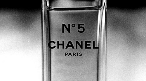 A black and white image of a close-up view of a Chanel No. 5 perfume bottle.