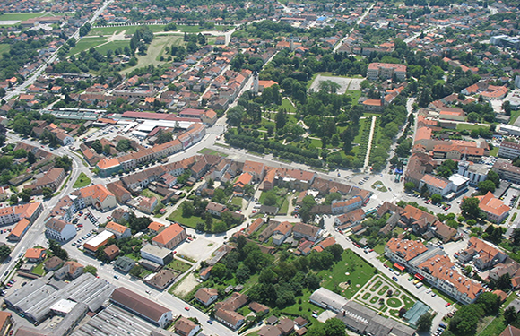 Aerial view of a town with dense building clusters, streets, and green spaces.