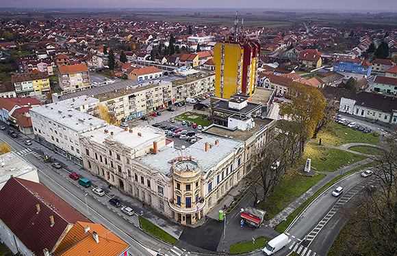 Aerial shot of a European town, featuring a classic building, a modern high-rise, residential areas and roads.