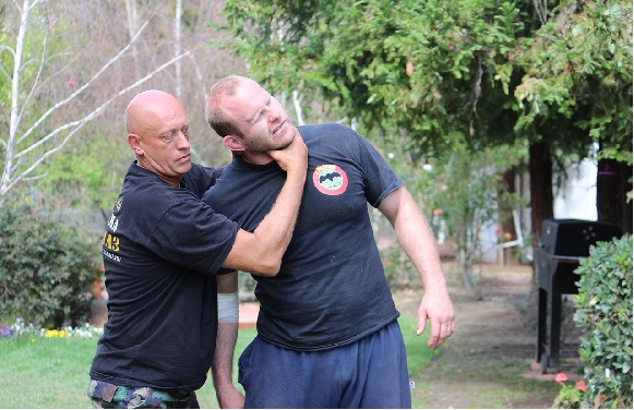 Two men practicing self-defense techniques outdoors.