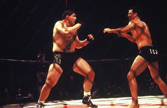 Two male boxers in a ring, one preparing to punch while the other is in a defensive stance.