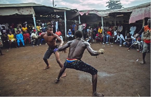 Two men engaged in a traditional wrestling match outdoors with spectators in the background.