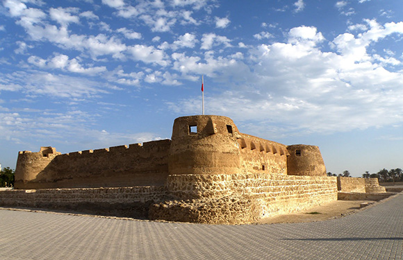 An image of an ancient fortress with a flag on top under a clear blue sky.