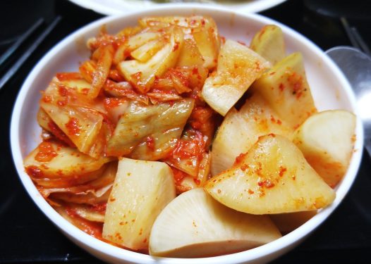 A bowl of kimchi, featuring fermented vegetables with a red, spicy seasoning.