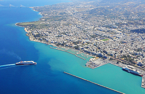 Aerial view of a coastal city with clear blue waters, docks, and urban buildings.