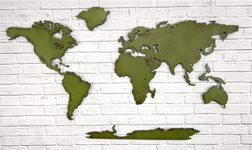 A metal world map with a cut-out design mounted on a white brick wall.